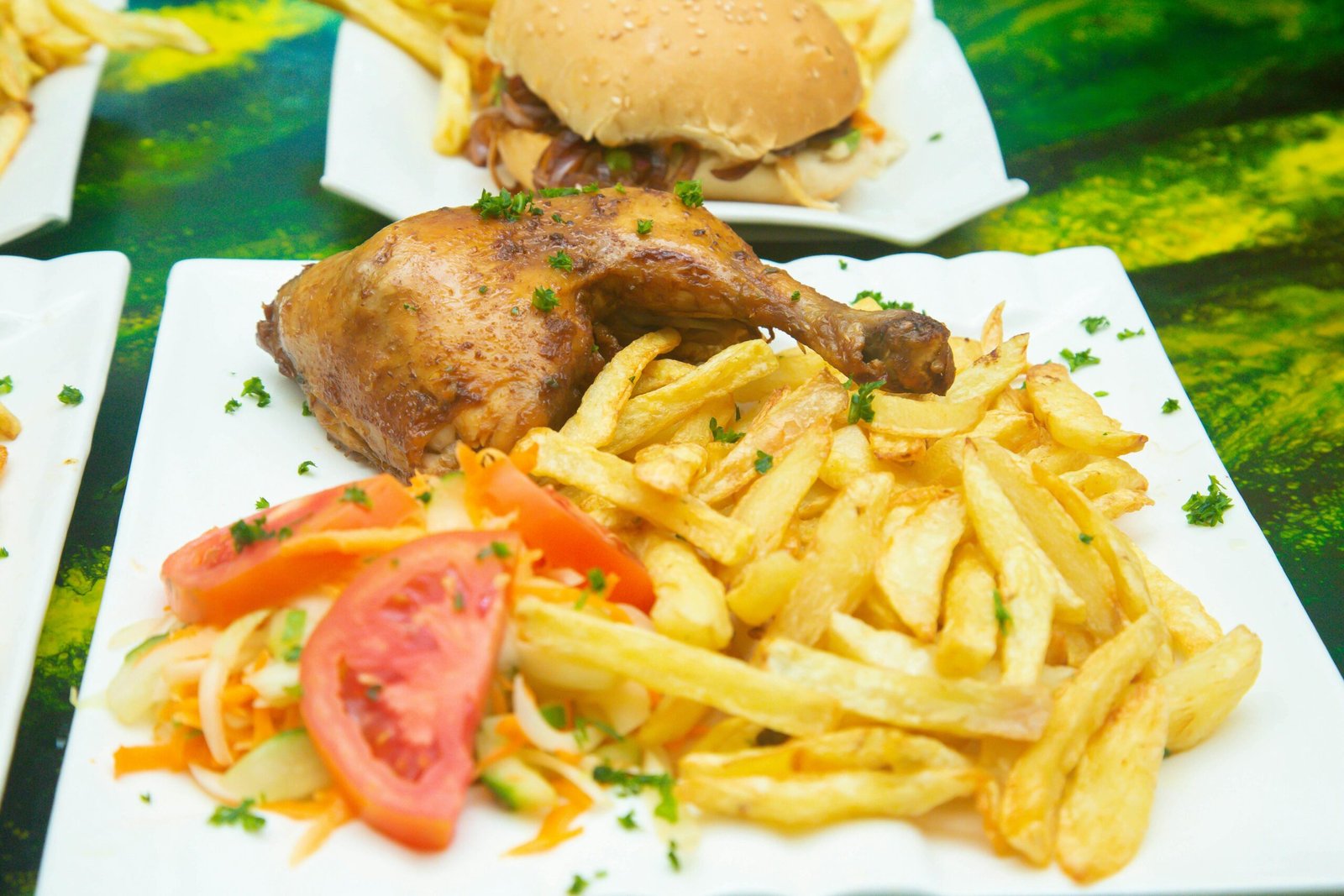 Tasty chicken meal with crispy fries, fresh tomato and salad on a white plate.